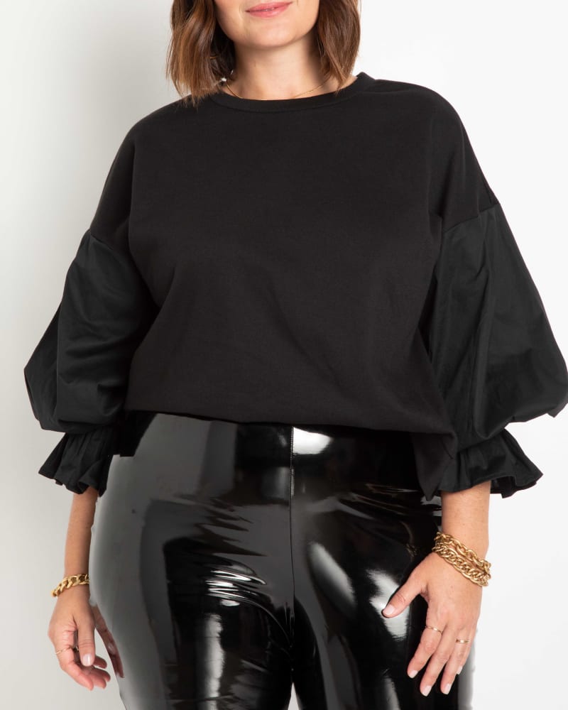 Front of a model wearing a size 14/16 Juniper Flounce Sleeve Sweatshirt in Totally Black by ELOQUII. | dia_product_style_image_id:236501